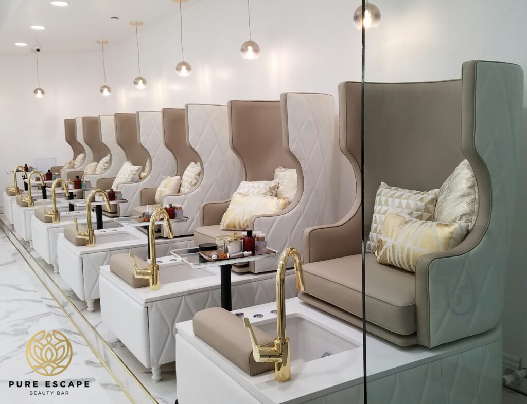 Row of pedicure chairs with gold faucets and white quilted accents.