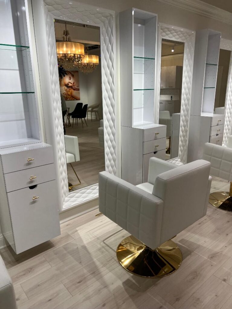 Salon setup with white quilted chairs, tall mirrors, and glass shelving.